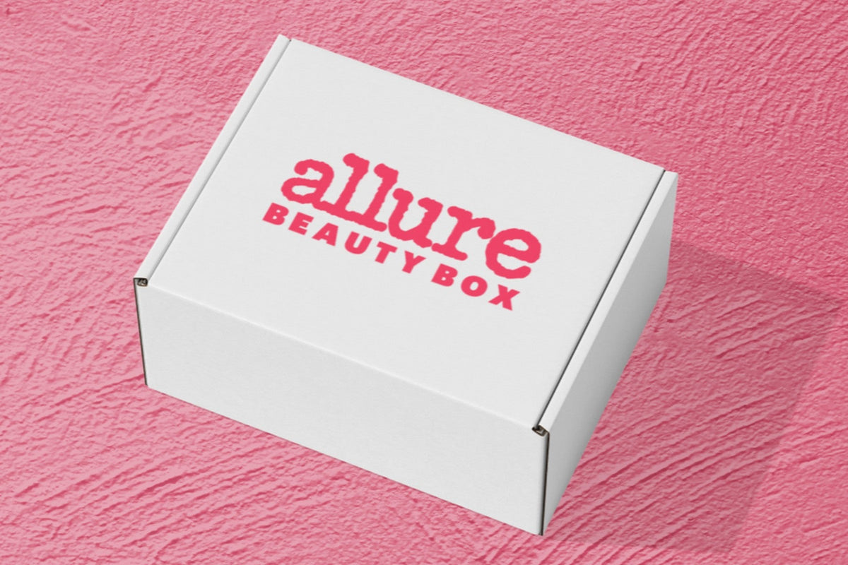 A white Allure Beauty Box shipping box with the pink allure BEAUTY BOX logo, on a pink textured surface
