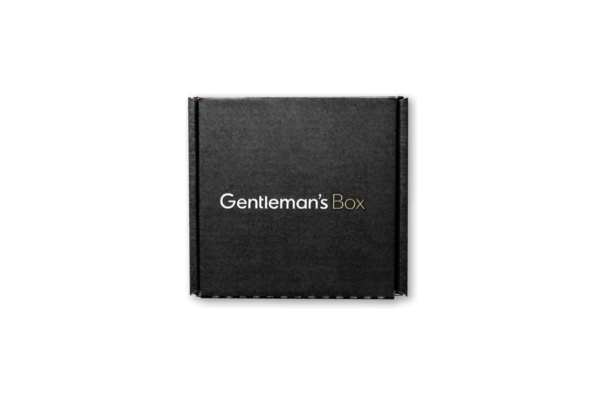 A black Gentleman’s Box subscription mailer box printed with the white and gold Gentleman’s Box wordmark