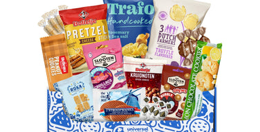 A Universal Yums box printed with the Universal Yums logo, filled with Dutch snacks including stroopwafels, Bolletje pretzel sticks, and Trafo potato chips