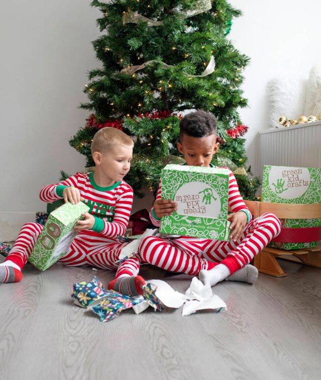 Kids opening Green Kids Crafts box near Christmas tree Kids opening Green Kids Crafts box near Christmas tree