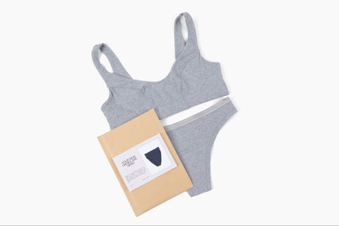 Gray seamless bralette and matching thong, with a notecard and a mailer included in the monthly subscription