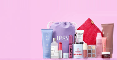 IPSY’s purple drawstring bag with the IPSY wordmark, surrounded by full-size beauty products including a Fenty Hair tube, The Ordinary serum, a Benefit mascara, First Aid Beauty cream, and a Wingme eyeshadow palette, on a pink background