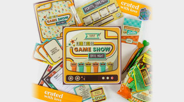 A Crated with Love Retro Game Show date night box surrounded by its game cards, points tracker, pens, and two orange bands printed with the crated with love logo