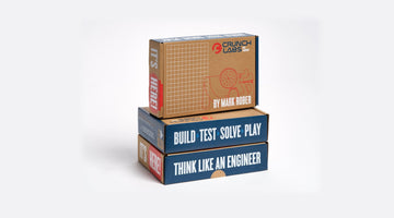 Three CrunchLabs Build Boxes stacked on a white background, the top box printed with the CrunchLabs logo and “By Mark Rober,” the lower two with “Build, Test, Solve, Play” and “Think Like an Engineer”