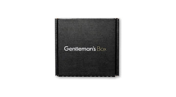 A black Gentleman’s Box subscription mailer box printed with the white and gold Gentleman’s Box wordmark