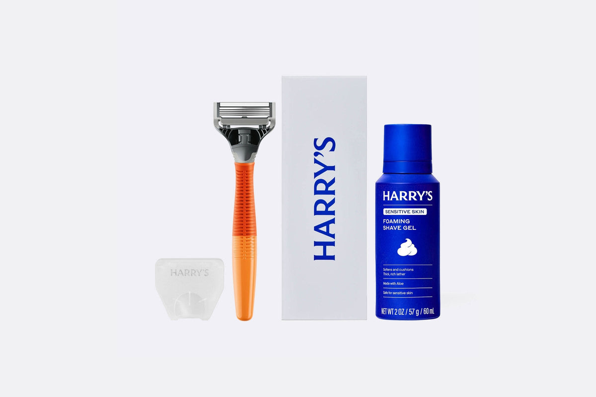 Harry’s Original Starter Set: an orange razor, a white box printed with the Harry’s logo, a blue can of Harry’s foaming shave gel, and a clear travel blade cover