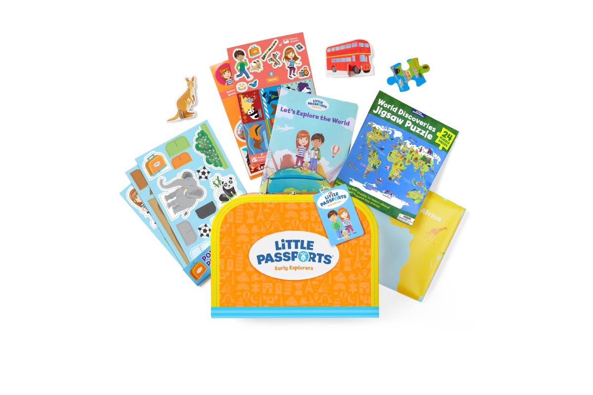 A Little Passports Early Explorers welcome kit: an orange suitcase printed with the Little Passports logo, surrounded by sticker sheets, a Let’s Explore the World booklet, a 24-piece world map puzzle, and pop-out animals.