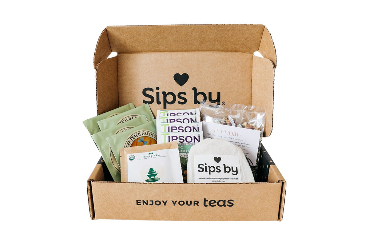 An open Sips by discovery box holding four teas from different tea brands and a Sips by muslin tea bag