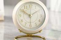 Retro style white, cream, and gold clock. The label says "quartz" and it is sitting on a marble tabel top