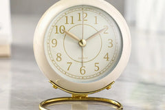 Retro style white, cream, and gold clock. The label says "quartz" and it is sitting on a marble tabel top