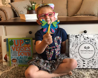Smiling child with craft and Owl Post Books kids subscription box, a holiday book club gift that brings joy and inspires young readers.