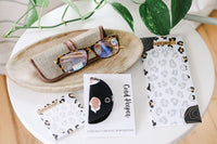 Ready for work with a pair of blue light glasses, as well as an animal print set of sticky notes, to-do list, + cord keeper.