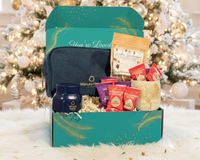 Senior Joy December Box displayed beside a Christmas tree, filled with curated self-care gifts for seniors.