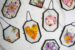 Framed pressed flowers in various shapes and colors displayed on a marble surface from The Adults & Crafts Crate subscription box