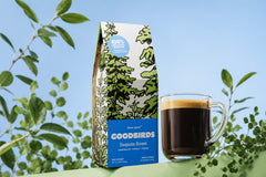 Two bags of coffee, a Goodbirds box and a cup of coffee, part of Goodbirds monthly coffee subscription of 2 12oz bags of coffee