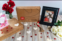 Grandbox Valentine's Day gift box with flowers, family photo frame, romantic card, and heart-shaped decorative details.