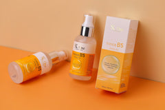 Close up photo of 2 skin care products with the colors orange and white. Laying on a orange table and with an orange wall behind it.