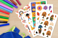 A selection of autumn themed stickers (pumpkins, flowers, trees) pictured on a desktop along with markers and a backpack.