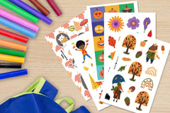 A selection of autumn themed stickers (pumpkins, flowers, trees) pictured on a desktop along with markers and a backpack.
