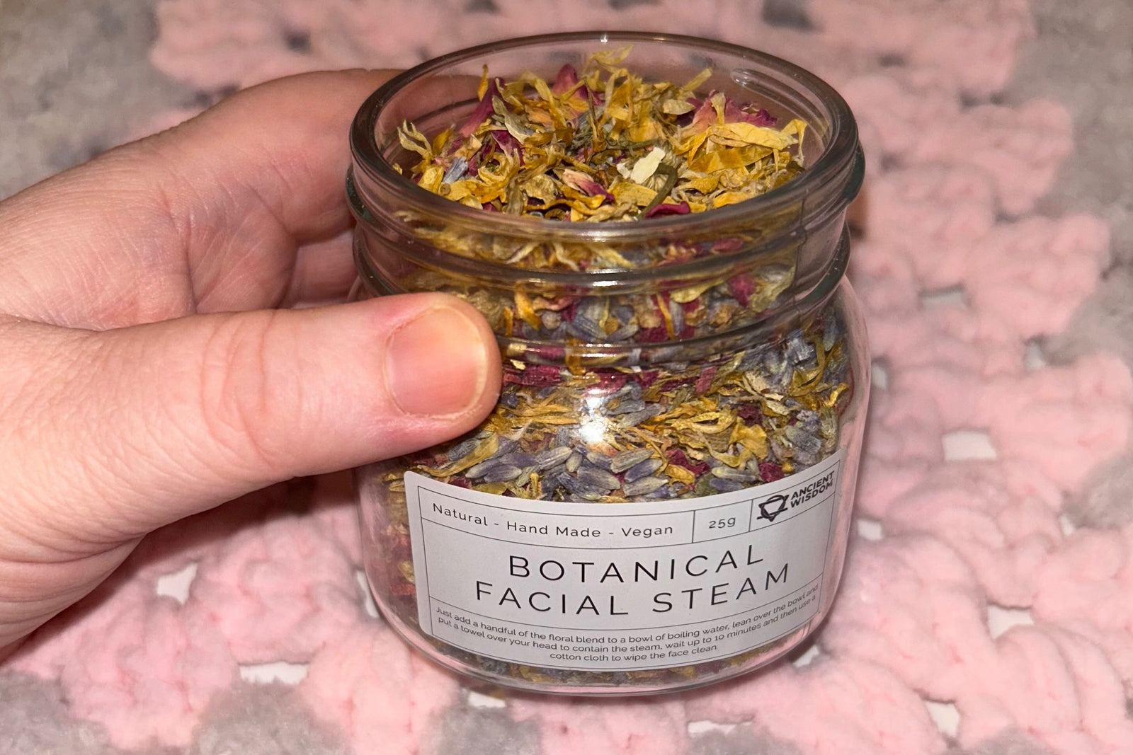 Customer holding a jar of botanical face steamer made from real flowers and herbs to add to hot water.
