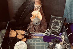 A black and gold quill, altar broom, rune set, and oracle deck in the Busy Witch Box subscription box