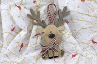 The layered wood reindeer ornament up close: antlers, a glossy black nose, freckled pink cheeks and a red gingham bow on tissue