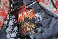 This is The Night House by Jo Nesbo with a red feather pen gift and a skull apron gift on top of a red and white bloody background