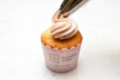 Bright lemon cupcakes topped with pink strawberry buttercream swirls and white sugar pearls in a baking kit setup