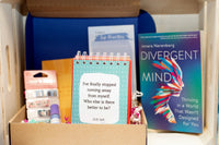 Sample boxes displayed on a crate, showing books, self care items, homeware, information cards, crafts and more