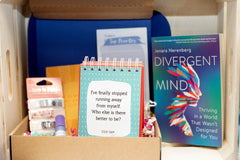 Sample boxes displayed on a crate, showing books, self care items, homeware, information cards, crafts and more