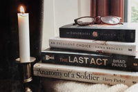 Brown box filled with a diverse collection of books in multiple genres, including crime thrillers, romance, and fantasy