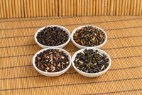 Four of The Tea Smith's house blends in white dishes: Blacksmith Blend, Applejack Festival, Black Bourbon Praline, Blueberry Lemon Oolong