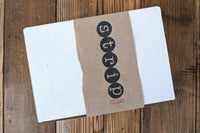 Strip Club Subscription Box shown closed with Strip Club Logo printed on a Kraft paper box sleeve with torn edges.