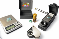 Gemological tools displayed with a GemFlip black box, including a precision scale, gemstones, and testing accessories, emphasizing professio