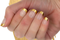 styled nail wraps displaying golden foil tips on each fingernail and transparent sections below the tips