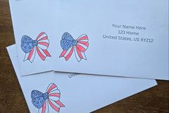 Three white envelopes with printed sample U.S. mailing addresses and red, white and blue patriotic bow designs featuring stars and stripes.