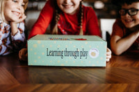 Three children excitedly showing off a Wiggle Worms Kit, filled with creative crafting supplies.....