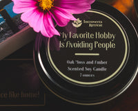 Introverts Read & Relax showing a candle, part of a book and a pink flower on a dark wood background,