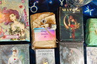tarot and Oracle decks wrapped in tissue and brown paper surrounded by unwrapped tarot and oracle decks and crystals 