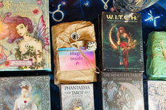 tarot and Oracle decks wrapped in tissue and brown paper surrounded by unwrapped tarot and oracle decks and crystals 