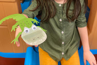 Young child holding a Wiggle Worms Kit, grinning and ready to start a fun craft project. She is holding a reptile craft.