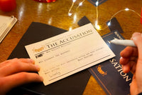 Close up photo of a persons hands holding a pen and a piece of paper with the words accusations and many more.