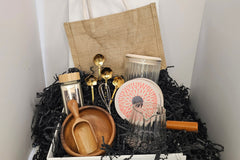 A beautifully curated set: jute bag, vanilla sugar, gold spoons, acacia bowl & scoop, glass jar, and measuring cup.