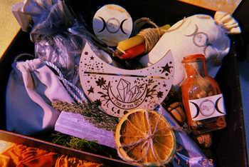 A variety of ritual items including candles, herbs, and a wooden talisman in the Busy Witch Box subscription box