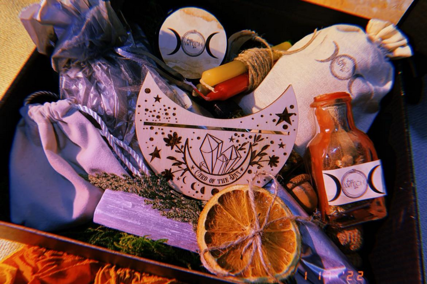 A variety of ritual items including candles, herbs, and a wooden talisman in the Busy Witch Box subscription box