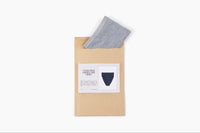 Pair of underwear (gray thong folded) peaking out of mailer along with a notecard from the subscription