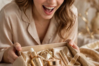 model is shown unboxing gold themed skincare products inside a gift box while being excited  unboxing the items one by one