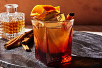 Classic Old Fashioned cocktail with an orange peel garnish, luxury cherries, and a crystal-clear ice