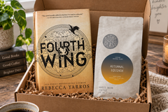 Hardcover fantasy book Fourth Wing by Rebecca Yarros paired with a bag of coffee in a monthly book subscription box