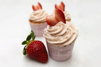 Bright lemon cupcakes topped with pink strawberry buttercream swirls and white sugar pearls in a baking kit setup